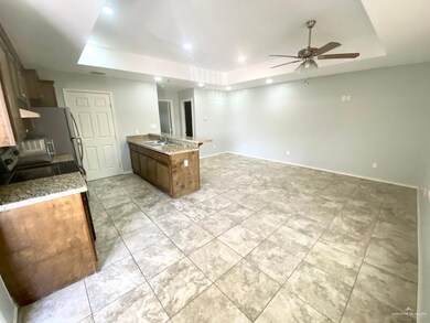 Kitchen with a tray ceiling, a peninsula, ceiling fan, light stone counters, and recessed lighting