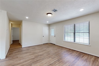 View from the dining area of the living room, with the secondary bathroom and bedrooms down the hallway.