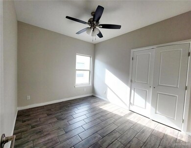 Unfurnished bedroom featuring a closet, baseboards, a ceiling fan, and dark wood-style flooring