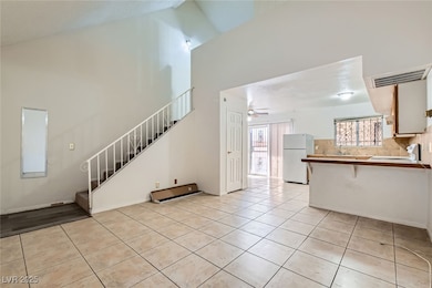 Unfurnished living room featuring stairs, high vau