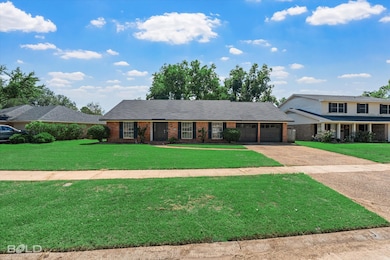 Traditional-style home featuring a front yard, brick siding, concrete driveway, and a garage