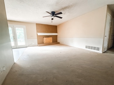 Unfurnished living room with a large fireplace, a ceiling fan, and a textured ceiling