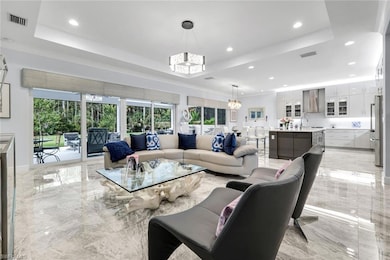 Living room featuring light marble finish floors, healthy amount of natural light, recessed lighting, and a raised ceiling