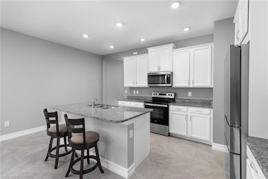Kitchen with a kitchen island with sink, dark ston