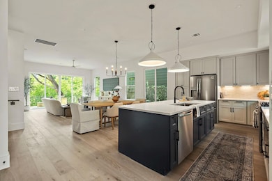 Kitchen featuring a sink, stainless steel appliances, open floor plan, decorative backsplash, and light countertops