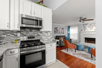 Kitchen featuring white cabinets, light stone coun