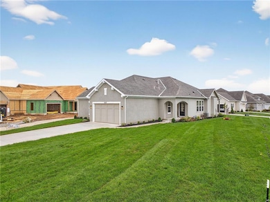View of front of house with driveway, a front yard, stucco siding, and a garage