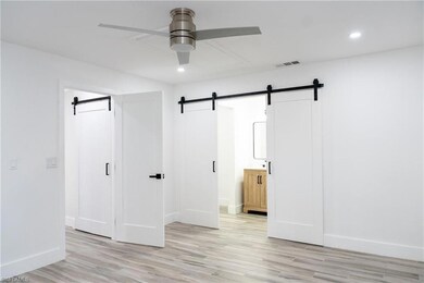 Unfurnished bedroom with a barn door, light wood-s