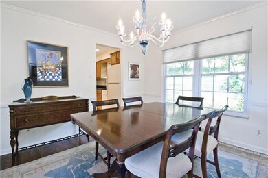 The dining room has a gleaming hardwood floor, cha