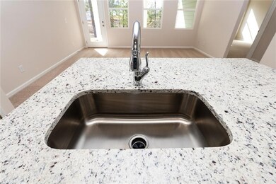 Kitchen view of a sink, light stone countertops, baseboards, and light carpet