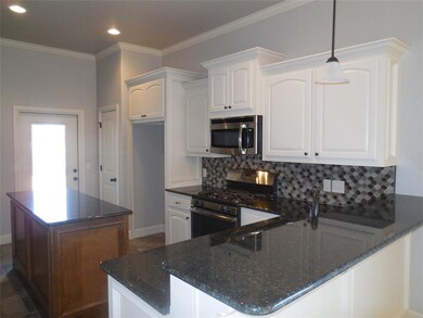 Kitchen featuring white cabinetry, stainless steel appliances, dark stone counters, decorative backsplash, and decorative light fixtures