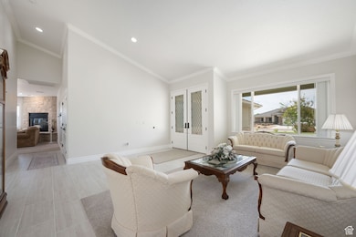 Main formal living room  & entry featuring a stone fireplace in family room, ornamental molding, high vaulted ceiling, and recessed lighting, 3-tone paint, front entry doors