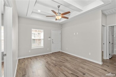 Spare room featuring light wood-style flooring, a tray ceiling, baseboards, and ceiling fan