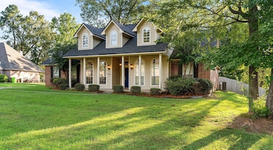 New england style home with a shingled roof, covered porch, and brick siding