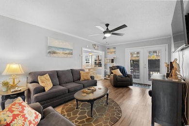 Living area featuring wood finished floors, a ceiling fan, french doors, and ornamental molding