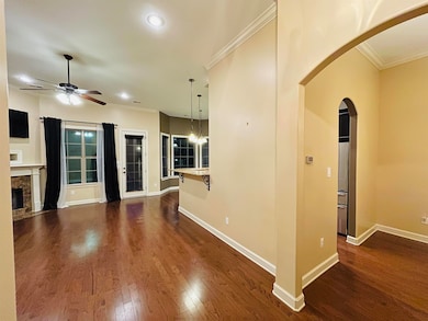 Unfurnished living room with arched walkways, ornamental molding, a ceiling fan, dark wood finished floors, and baseboards