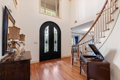 Entrance foyer with ornamental molding, a towering ceiling, light wood-type flooring, and a healthy amount of sunlight