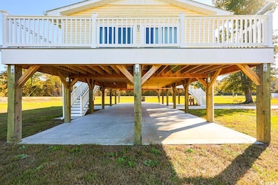 Surrounding community with a deck, a carport, stairs, and a lawn