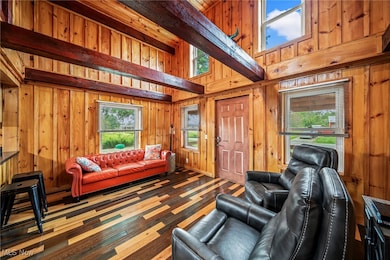 Living room with a towering ceiling, beamed ceiling, wood walls, and wood finished floors