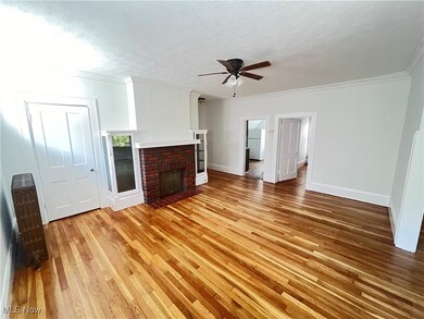 Unfurnished living room featuring a textured ceiling, hardwood / wood-style floors, ceiling fan, and a brick fireplace