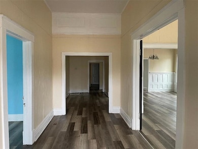 Hall featuring baseboards, crown molding, and dark wood finished floors