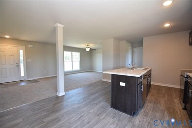 Kitchen with open floor plan, recessed lighting, electric range, a kitchen island with sink, and dark brown cabinets