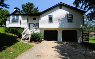 Split foyer home with an attached garage, driveway, a chimney, a front yard, and stairway