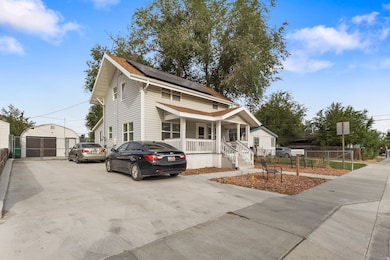 View of front of home featuring covered porch, an outbuilding, a garage, roof mounted solar panels, and driveway