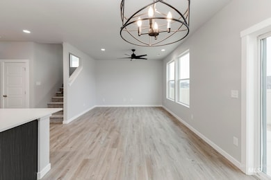 Unfurnished living room featuring a chandelier, light wood-type flooring, recessed lighting, stairway, and a ceiling fan