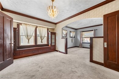 Dining room with natural wood crown molding, carpet flooring over hardwood floors and built in cabinets and window seat