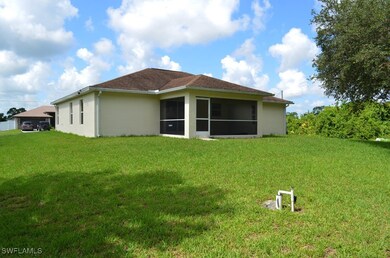 Back of house with stucco siding, a lawn, and a su