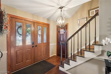 Entryway featuring dark wood finished floors, a chandelier, and stairway