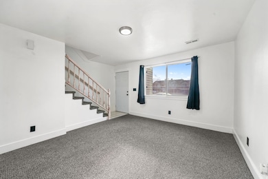 Carpeted empty room featuring stairway and baseboards