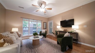Living room featuring crown molding, wood finished floors, and ceiling fan