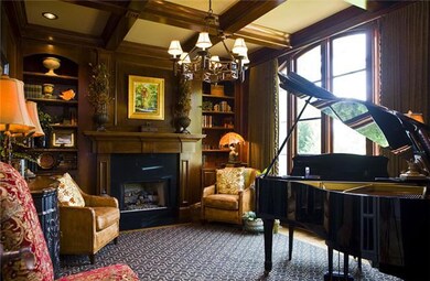 The library features a coffered ceiling and gas fireplace and built in custom book cases.
