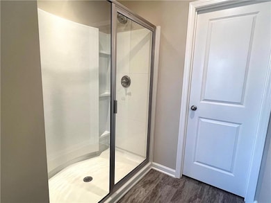 Bathroom featuring a stall shower, wood finished f