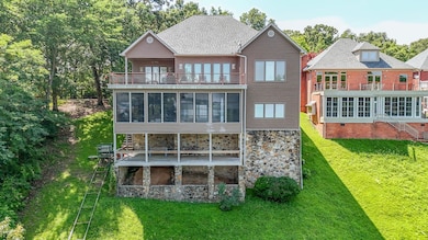 Rear view of property with a balcony, a sunroom, and a lawn
