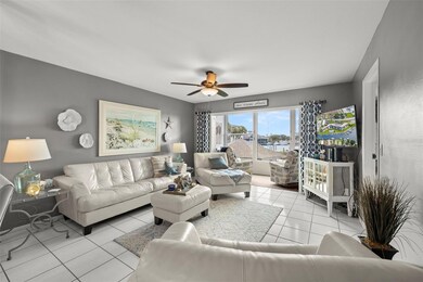 Charming coastal themed move-in ready condo that has all the views (canal, pool and city)! This is the main living area of the home with on-trend paint choices, scraped ceiling, ceiling fan, ceramic tile flooring AND an enclosed balcony with windows to the ceiling!
