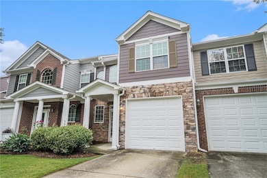 View of property featuring concrete driveway, stone siding, and an attached garage