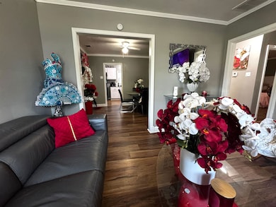 Living room with crown molding and wood finished floors