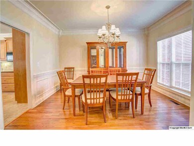 Formal Dining Room features chandelier, wood floors, extensive crown molding, chair rail, wainscoting, and a window with a view.