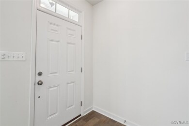 Doorway with dark wood-style floors and baseboards