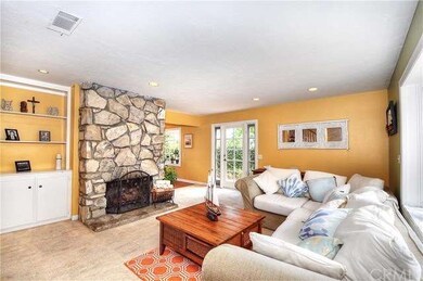 Living room with stone fireplace, built-ins, and r