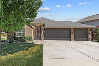 Ranch-style house with a shingled roof, brick siding, driveway, a garage, and a front yard