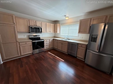 Kitchen featuring paneled fridge, light brown cabinets, range, and light countertops