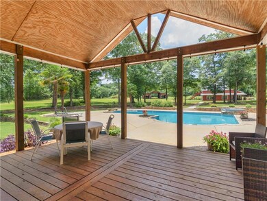 Wooden terrace featuring a patio area, view of scattered trees, and a pool with connected hot tub