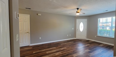 Foyer featuring dark wood-style flooring, a ceiling fan, a textured ceiling, and baseboards