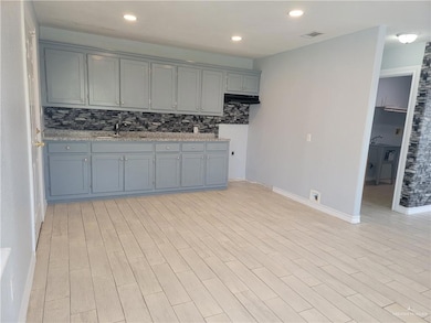 Kitchen with a sink, tasteful backsplash, baseboards, gray cabinetry, and recessed lighting