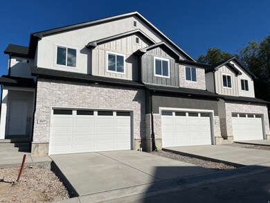 View of front facade with stone siding, driveway, an attached garage, and board and batten siding