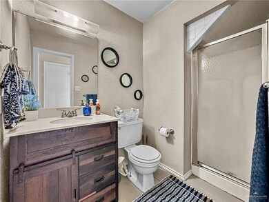 Bathroom with tile patterned floors, a shower with shower door, vanity, and toilet
